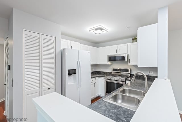 kitchen featuring white cabinets, sink, dark hardwood / wood-style floors, kitchen peninsula, and stainless steel appliances