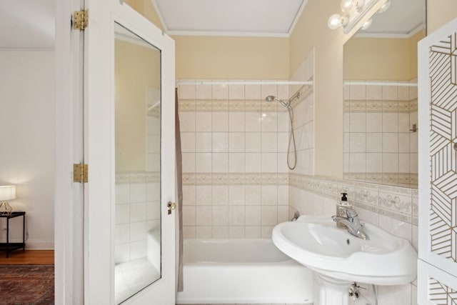 bathroom with sink, crown molding, tiled shower / bath, hardwood / wood-style flooring, and tile walls