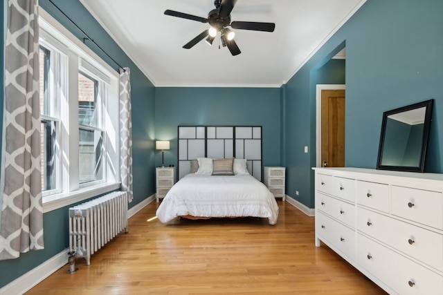 bedroom featuring ceiling fan, radiator heating unit, crown molding, and light hardwood / wood-style flooring