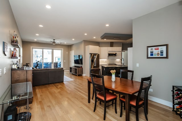 dining area with ceiling fan, sink, and light wood-type flooring