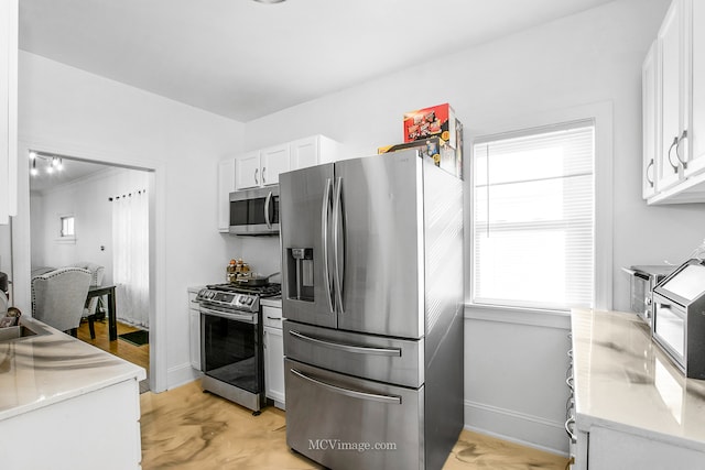 kitchen featuring light hardwood / wood-style flooring, white cabinets, a healthy amount of sunlight, and appliances with stainless steel finishes