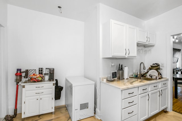 kitchen featuring white cabinets, refrigerator, light hardwood / wood-style flooring, and sink