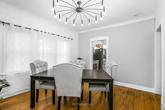 dining area featuring wooden walls, hardwood / wood-style flooring, ornamental molding, and a notable chandelier