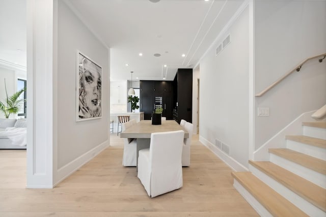 dining space with light hardwood / wood-style floors, crown molding, and a wealth of natural light