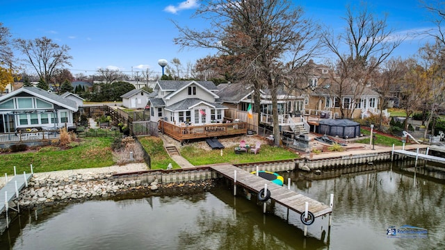 view of dock featuring fence, a deck with water view, a yard, and a residential view