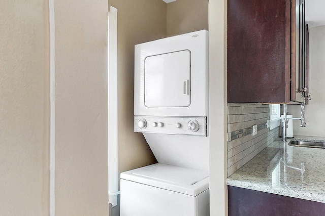 clothes washing area featuring stacked washer / drying machine and sink