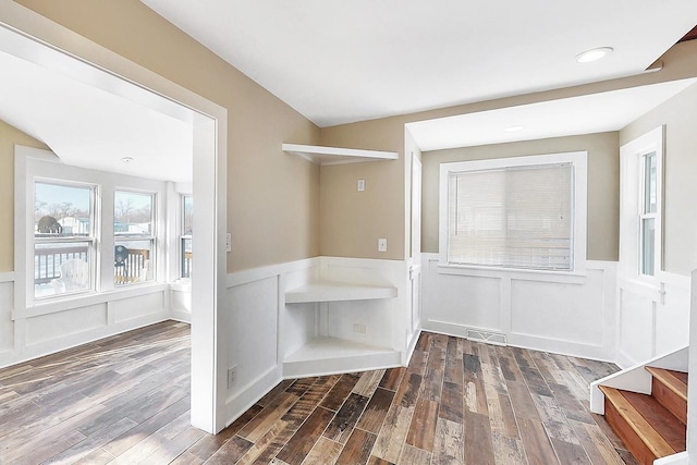 interior space featuring a decorative wall, a wainscoted wall, wood finished floors, and visible vents