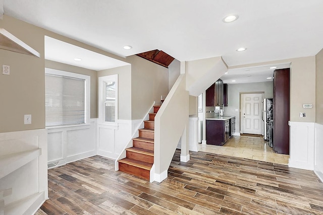 stairs with wainscoting, wood finished floors, recessed lighting, and visible vents