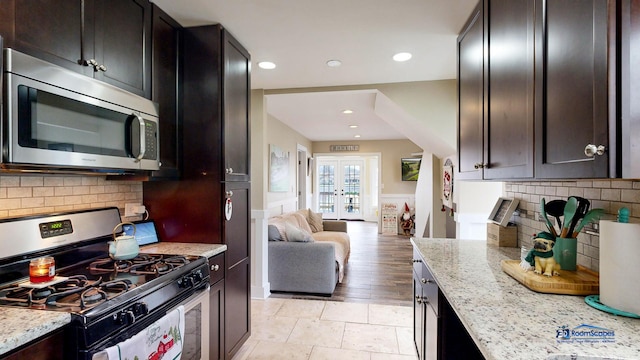 kitchen with dark brown cabinets, light stone countertops, french doors, and appliances with stainless steel finishes