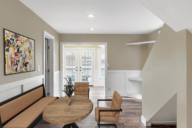 sitting room featuring french doors, dark wood-style flooring, recessed lighting, a decorative wall, and wainscoting