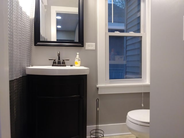 bathroom with toilet, vanity, and baseboards