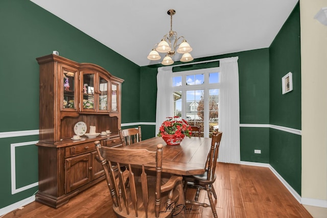 dining area featuring wood-type flooring and an inviting chandelier