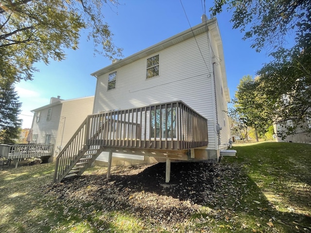 back of property featuring a deck and a lawn