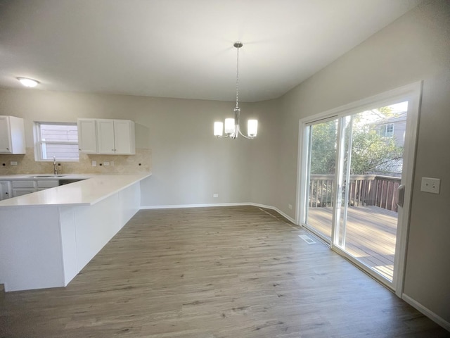 kitchen featuring pendant lighting, light hardwood / wood-style floors, and white cabinetry