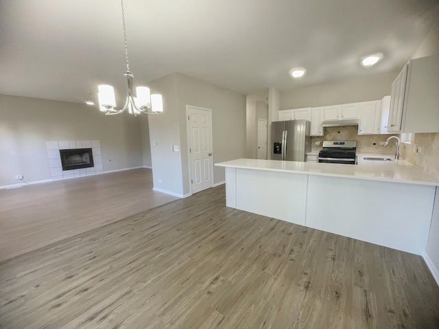 kitchen featuring stainless steel appliances, sink, pendant lighting, light hardwood / wood-style flooring, and white cabinetry