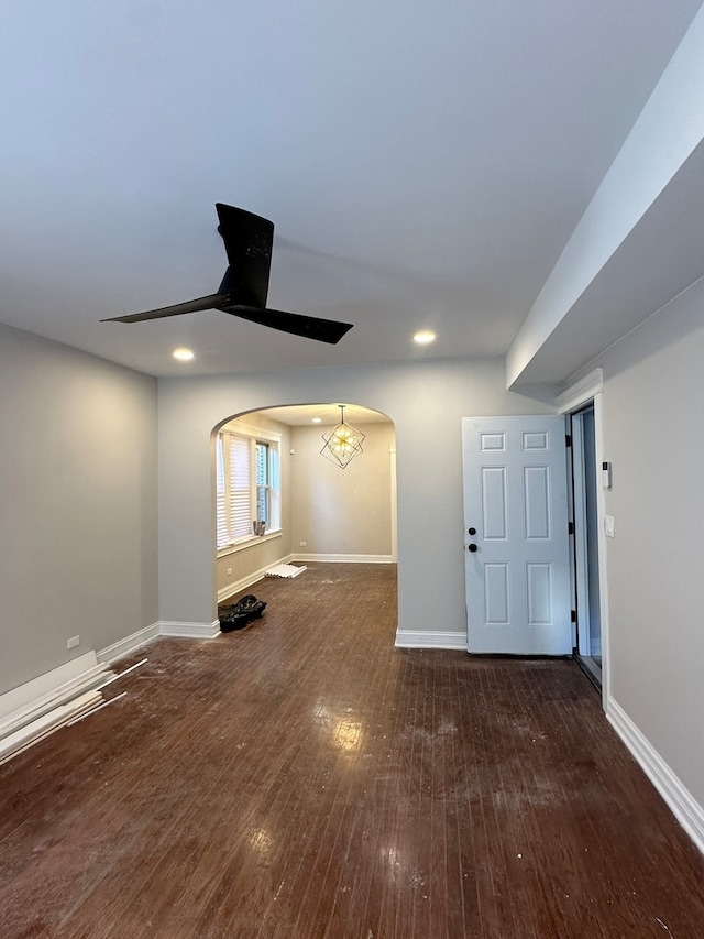 unfurnished living room featuring dark hardwood / wood-style flooring and ceiling fan with notable chandelier