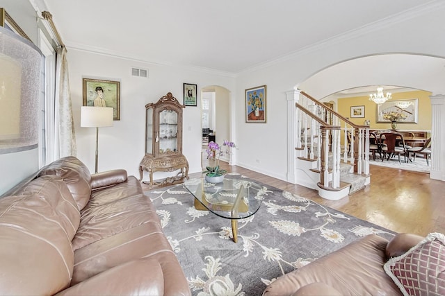 living area with visible vents, arched walkways, stairway, ornamental molding, and wood finished floors