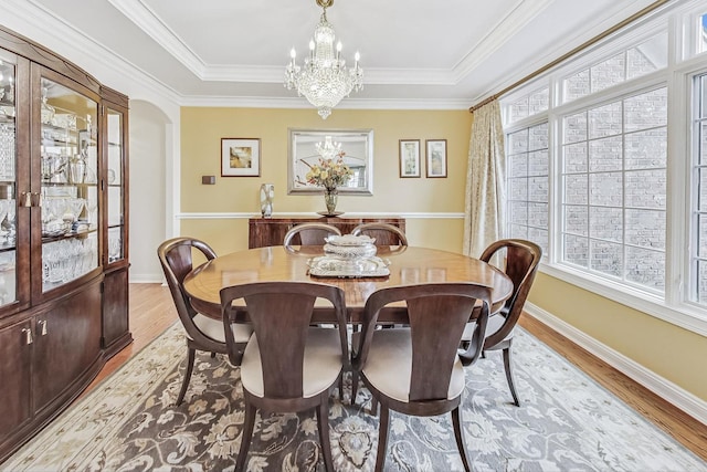 dining room featuring baseboards, crown molding, wood finished floors, and a notable chandelier