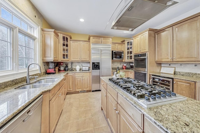 kitchen featuring light tile patterned floors, light brown cabinetry, a sink, built in appliances, and beverage cooler