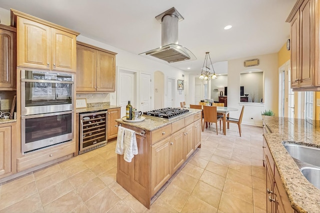 kitchen with light stone counters, wine cooler, appliances with stainless steel finishes, a center island, and island exhaust hood