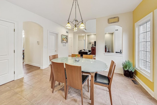 dining room featuring arched walkways, light tile patterned floors, visible vents, and baseboards