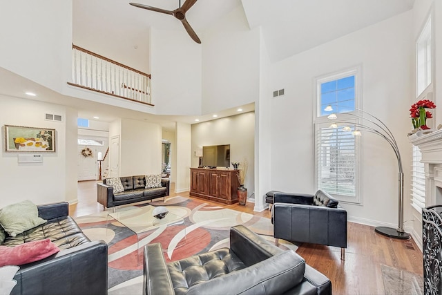 living room with a fireplace, stairway, ceiling fan, wood finished floors, and baseboards