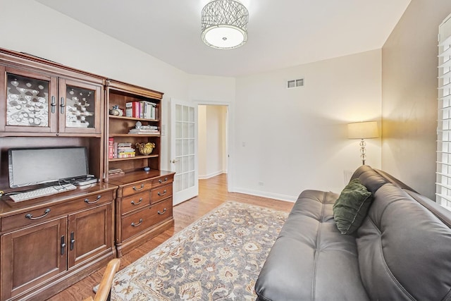 office area with light wood-type flooring, baseboards, visible vents, and french doors