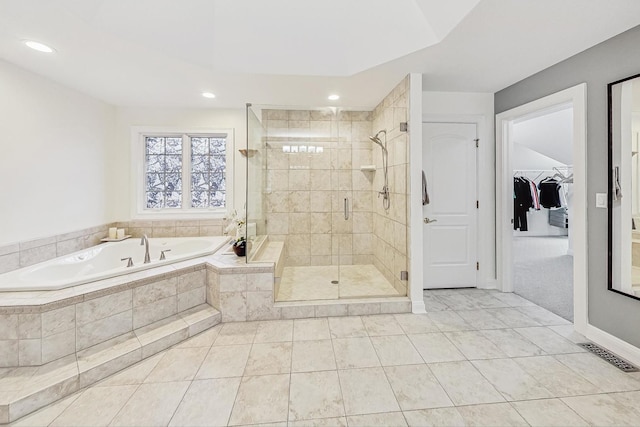 bathroom with a walk in closet, a garden tub, recessed lighting, visible vents, and a stall shower