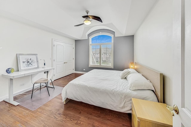 bedroom featuring baseboards, ceiling fan, wood finished floors, vaulted ceiling, and a closet