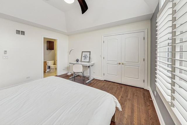 bedroom featuring visible vents, connected bathroom, vaulted ceiling, wood finished floors, and baseboards