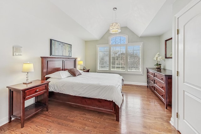 bedroom with vaulted ceiling, baseboards, and wood finished floors