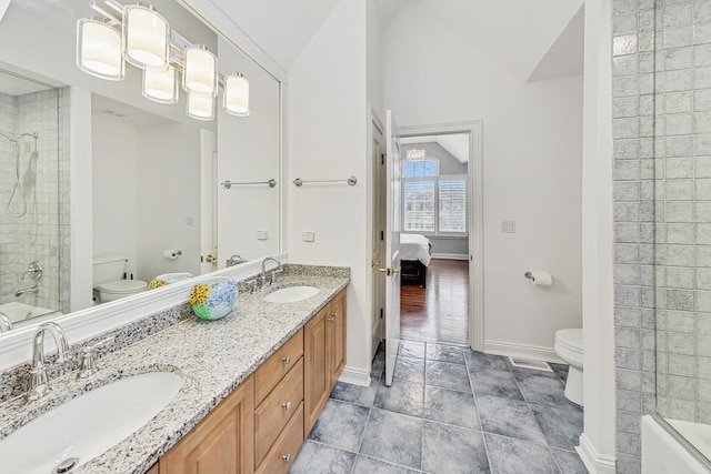 ensuite bathroom featuring vaulted ceiling, a sink, and toilet