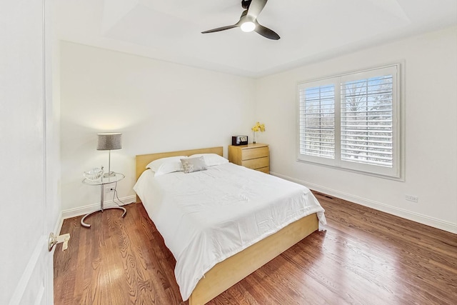 bedroom featuring a ceiling fan, baseboards, and wood finished floors