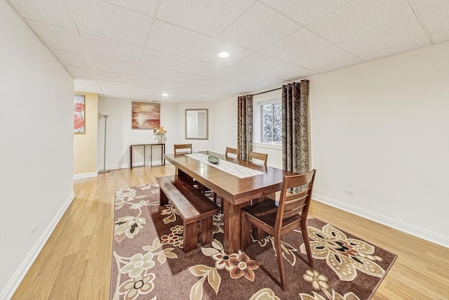 dining area with recessed lighting, light wood-type flooring, a paneled ceiling, and baseboards