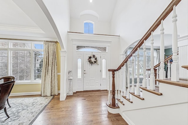 entryway with a high ceiling, stairway, wood finished floors, and crown molding