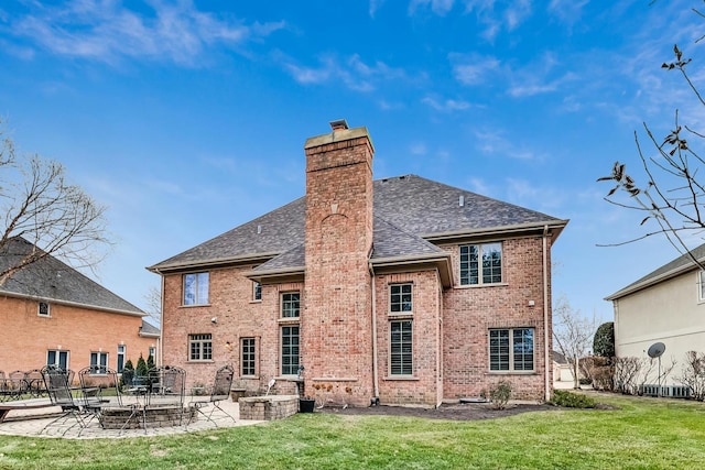 back of house featuring a yard, brick siding, a patio, and a chimney