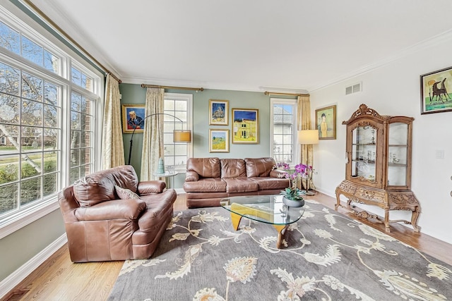 living area with plenty of natural light, visible vents, wood finished floors, and ornamental molding