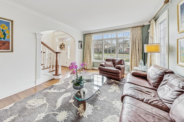 living area with stairway, arched walkways, wood finished floors, and ornamental molding