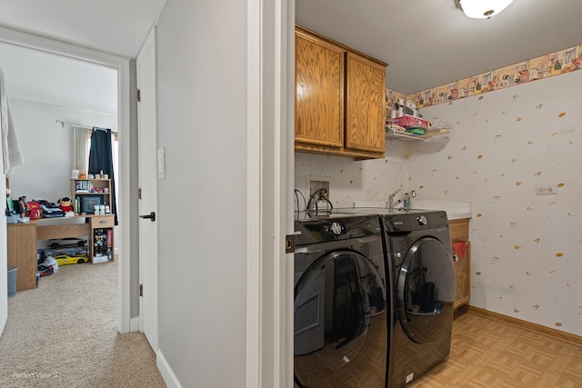 clothes washing area with washer and dryer, light parquet floors, and cabinets