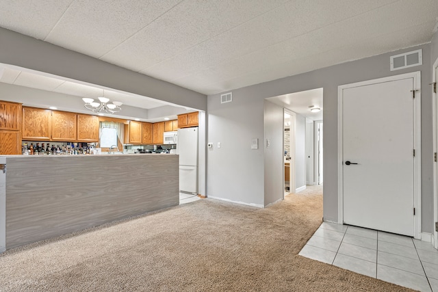 kitchen featuring white appliances, light colored carpet, and a notable chandelier