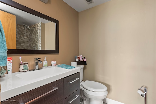 bathroom with tiled shower, vanity, and toilet