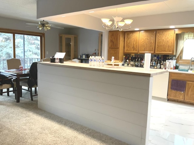 kitchen with kitchen peninsula, plenty of natural light, pendant lighting, and ceiling fan with notable chandelier