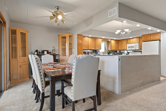 dining room with ceiling fan with notable chandelier and light colored carpet