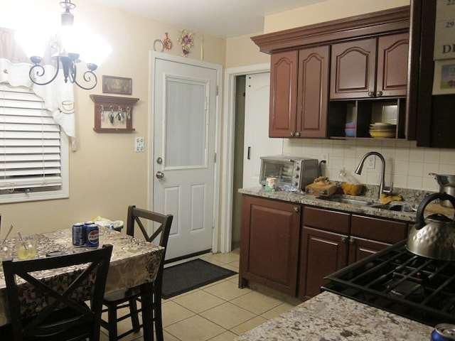 kitchen with backsplash, light stone counters, dark brown cabinetry, sink, and light tile patterned flooring