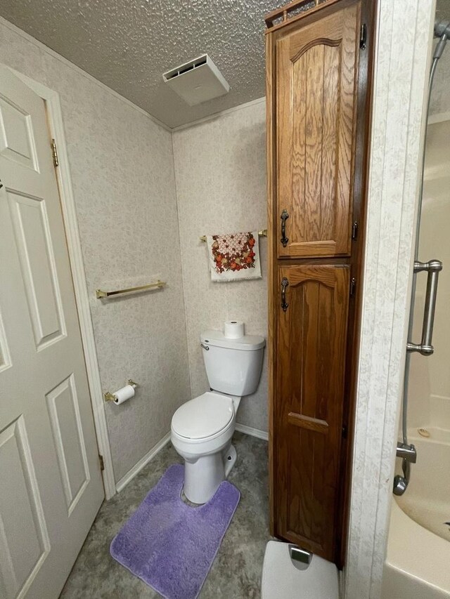 bathroom with a textured ceiling, bathing tub / shower combination, and toilet