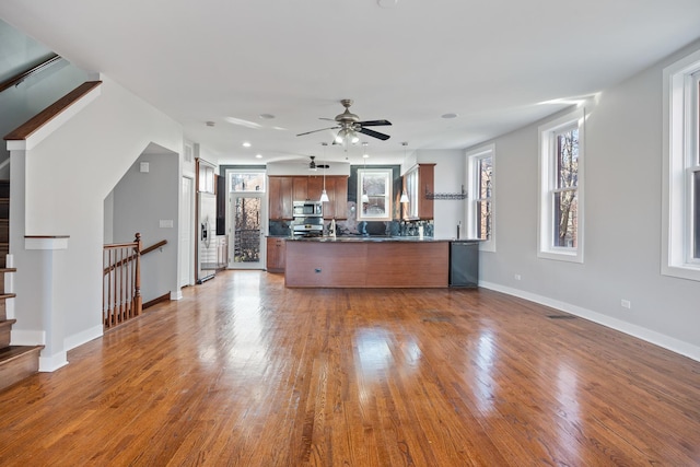 kitchen with ceiling fan, stainless steel appliances, backsplash, kitchen peninsula, and hardwood / wood-style flooring