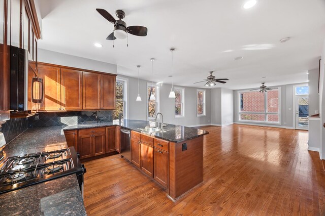 kitchen featuring sink, hanging light fixtures, stainless steel appliances, backsplash, and light wood-type flooring