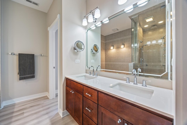 bathroom with hardwood / wood-style floors, vanity, and a shower with shower door