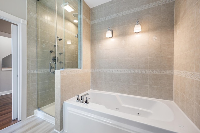 bathroom with hardwood / wood-style floors, tile walls, and independent shower and bath