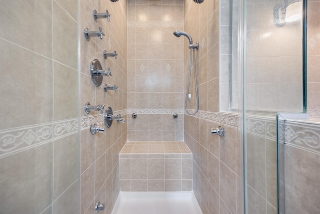 bathroom with a tile shower and tile walls